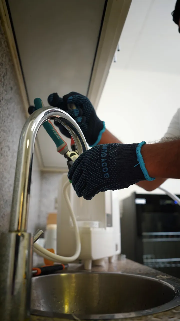 The EcoLuxia installation team fitting a K8: the unit lifted out of its box, a diverter fitted to the kitchen tap, the tank and the filter put in place.